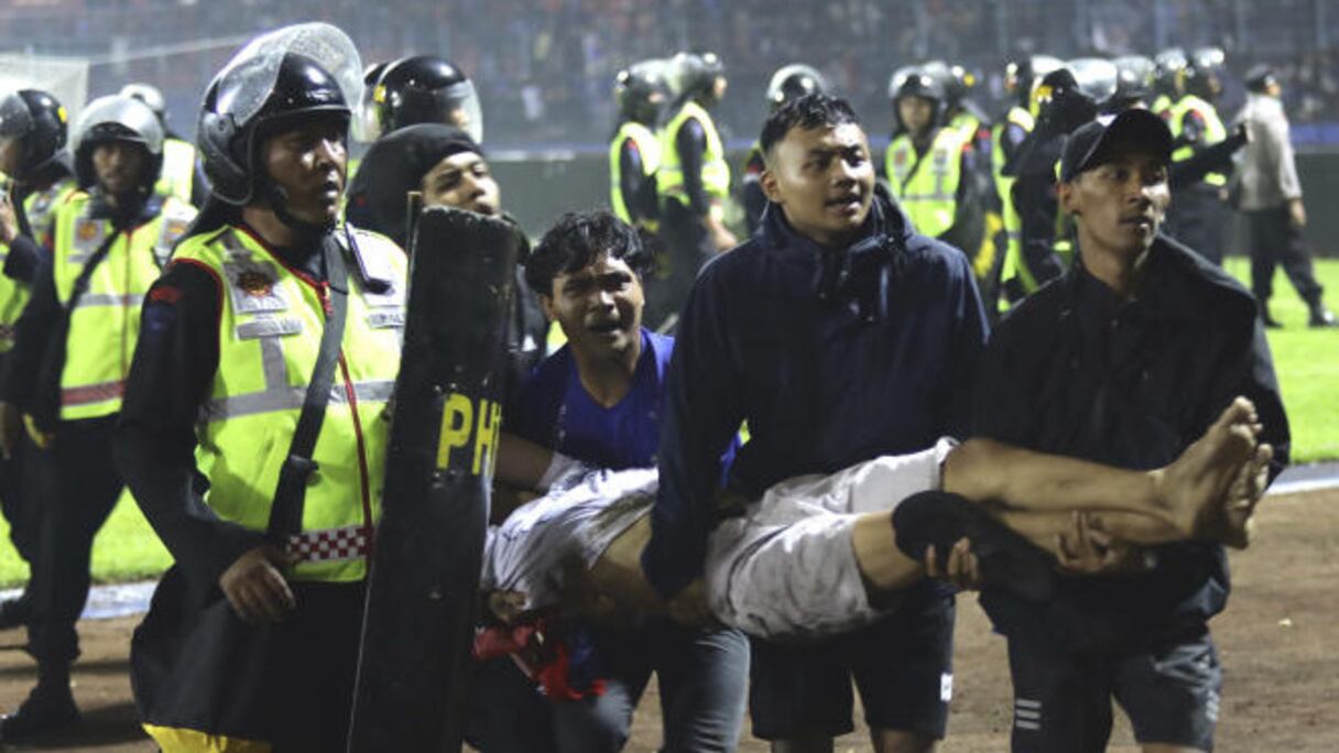 Des supporteurs portent un blessé lors de confrontations entre supporteurs dans le stade Kanjuruhan, à Malang, dans l’est de Java, en Indonésie, le 1er octobre 2022.