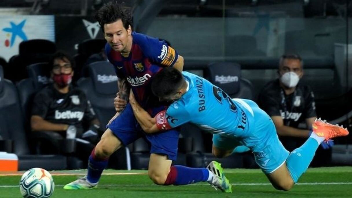 Lionel Messi plaqué par un défenseur.