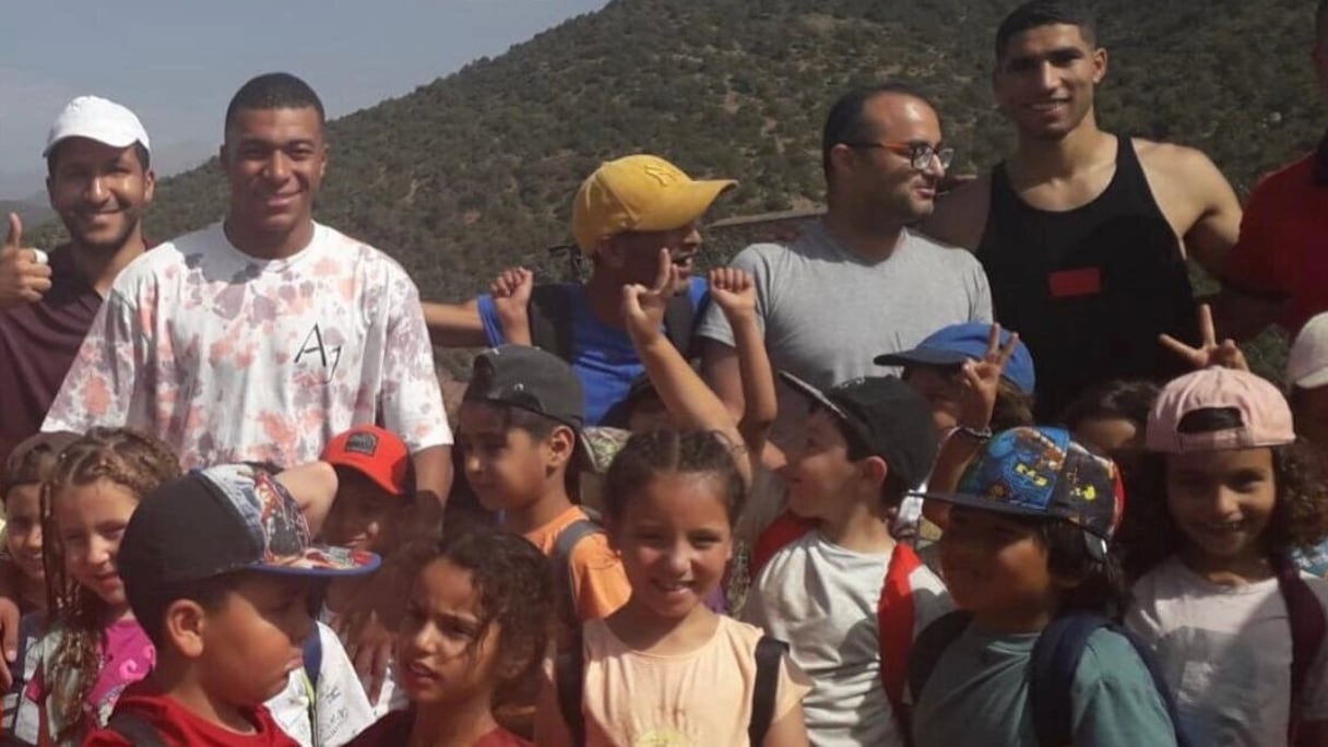 Achraf Hakimi et Kylian Mbappé prenant la pose avec des jeunes dans un village dans le province d'Al Haouz.