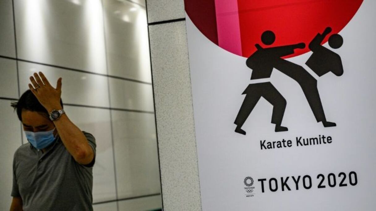 Un passant portant un masque devant une affiche des JO de Tokyo, dans le quartier de Shinjuku, le 12 juin 2020.