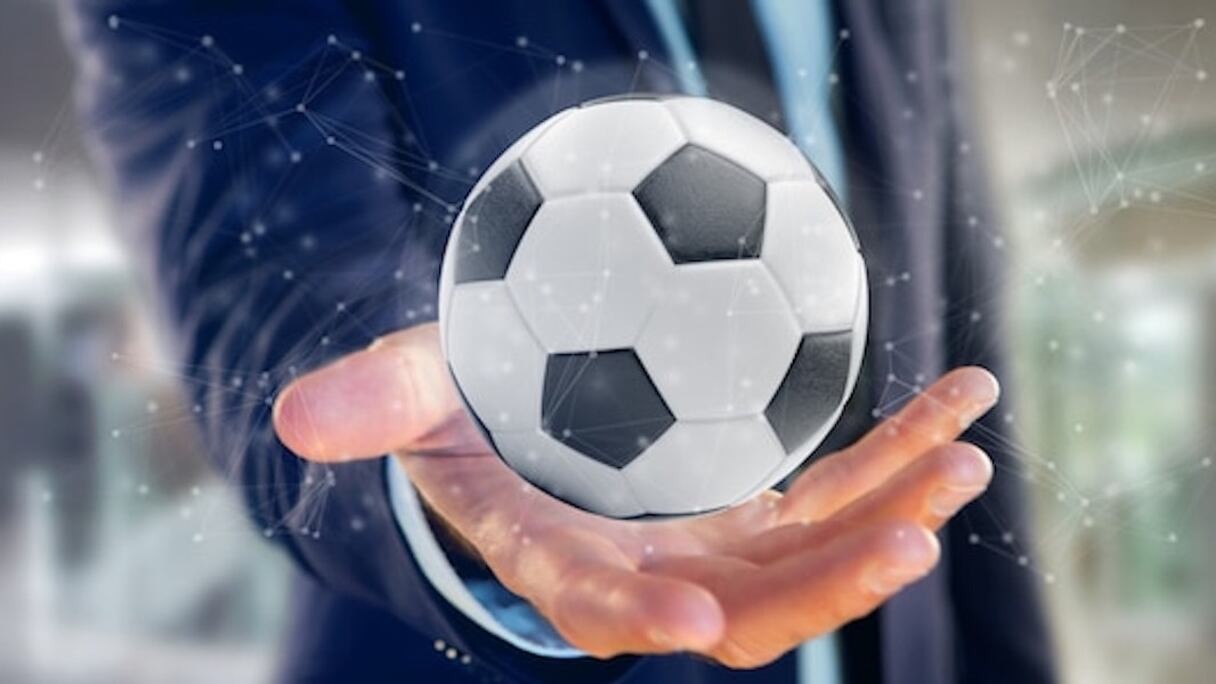 Homme tenant un ballon de foot.