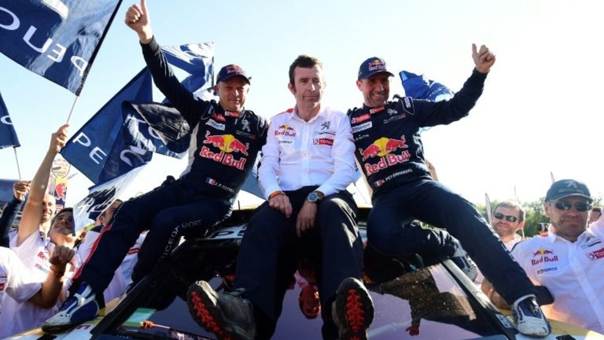 Stéphane Peterhansel (d), son copilote Jean-Paul Cottret (g) et le team manager Peugeot Bruno Famin fêtent leur succès dans le Dakar, le 14 janvier 2017 à Rio Cuarto en Argentine.