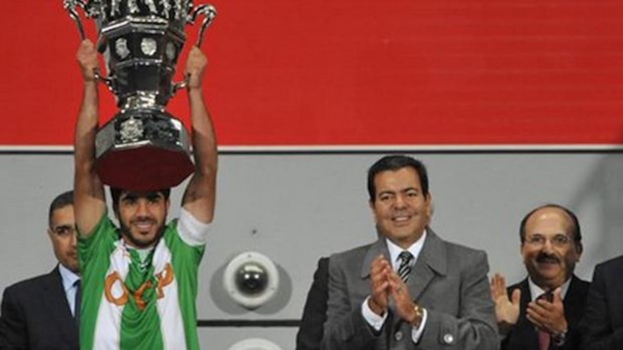 Le capitaine de l'OCK brandissant la Coupe du trône, applaudi par le prince Moulay Rachid.