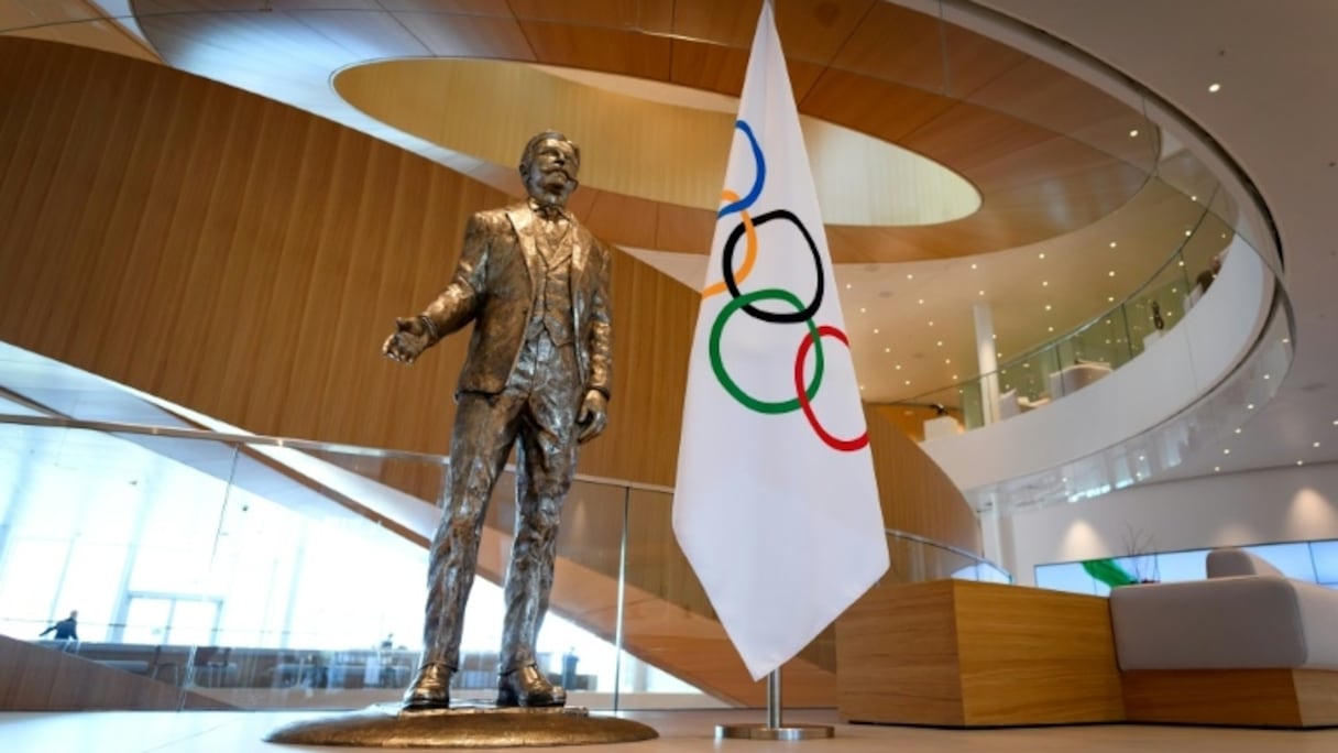 La statue du Baron Pierre-de-Coubertin, fondateur des Jeux de l'ère moderne, à côté du drapeau olympique dans le hall du siège du Comité international olympique le 3 mars 2020 à Lausanne.