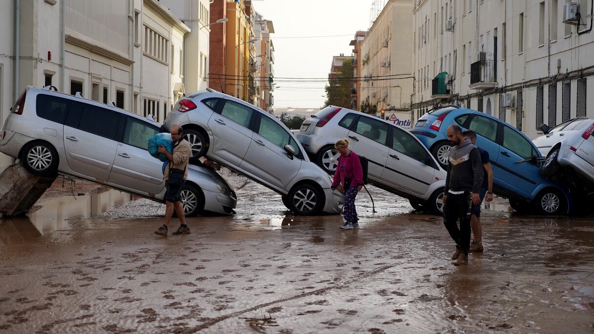 Des habitants passent devant des voitures empilées à la suite d'inondations meurtrières dans le quartier de De la Torre à Valence, au sud de Valence, dans l'est de l'Espagne, le 30 octobre 2024.