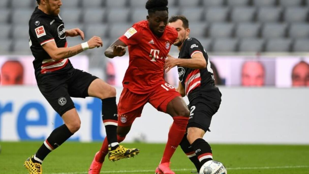 Le milieu canadien du Bayern, Alphonso Davies (c), aux prises avec le milieu autrichien de Düsseldorf, Kevin Stöger (d), lors du match de Bundesliga à Munich, le 30 mai 2020.