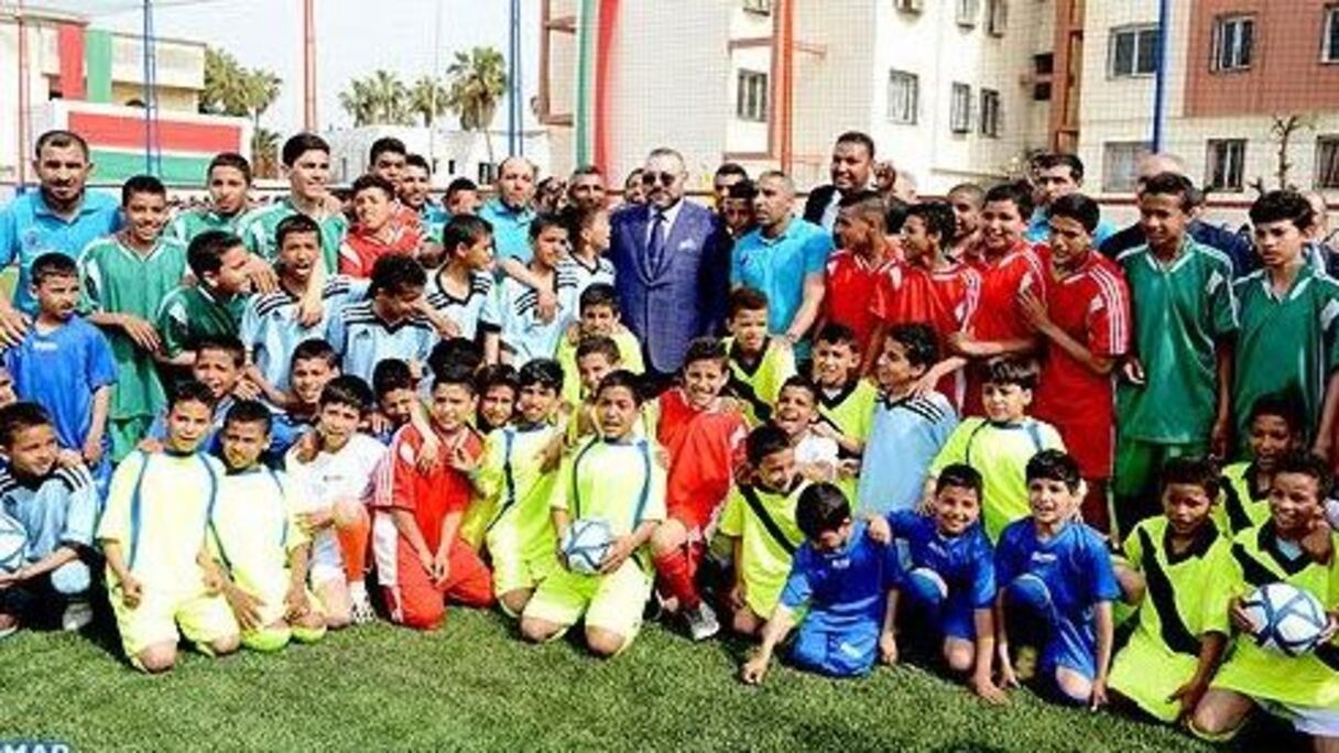 Le roi Mohammed VI en photo souvenir avec des jeunes lors de l'inauguration d'un terrain de proximité